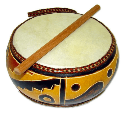 A round drum with yellow, orange, brown, and black designs burned into the sides with a stick resting on top